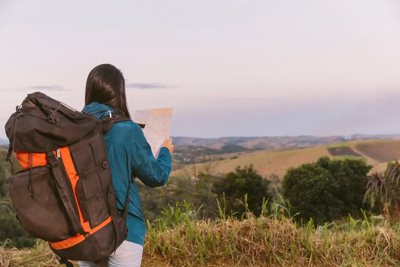 Eine Frau mit Reiserucksack betrachtet eine Karte.