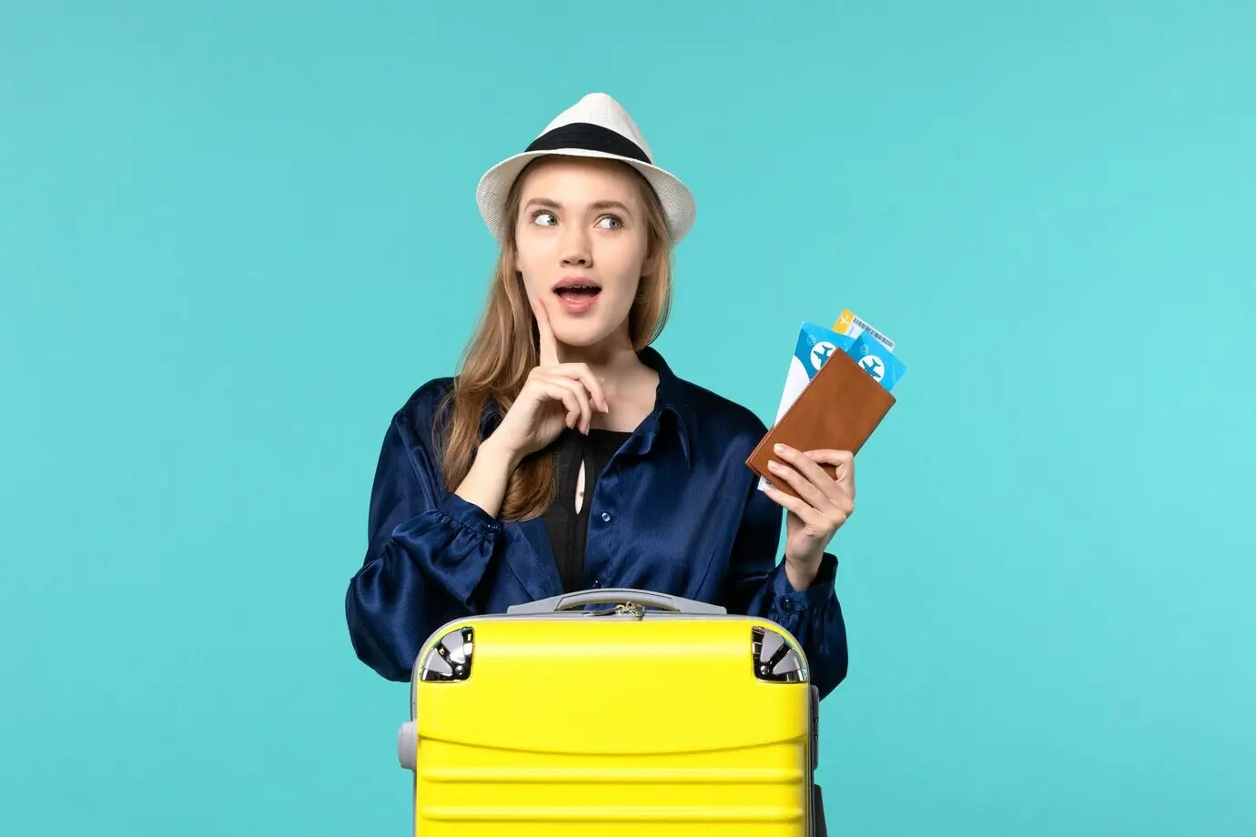 Vorderansicht einer jungen Frau, die Tickets in der Hand hält und sich auf eine Reise vorbereitet, vor hellblauem Hintergrund: Reise, Fahrt, Flugzeug, Meer, Urlaub, Reisen.